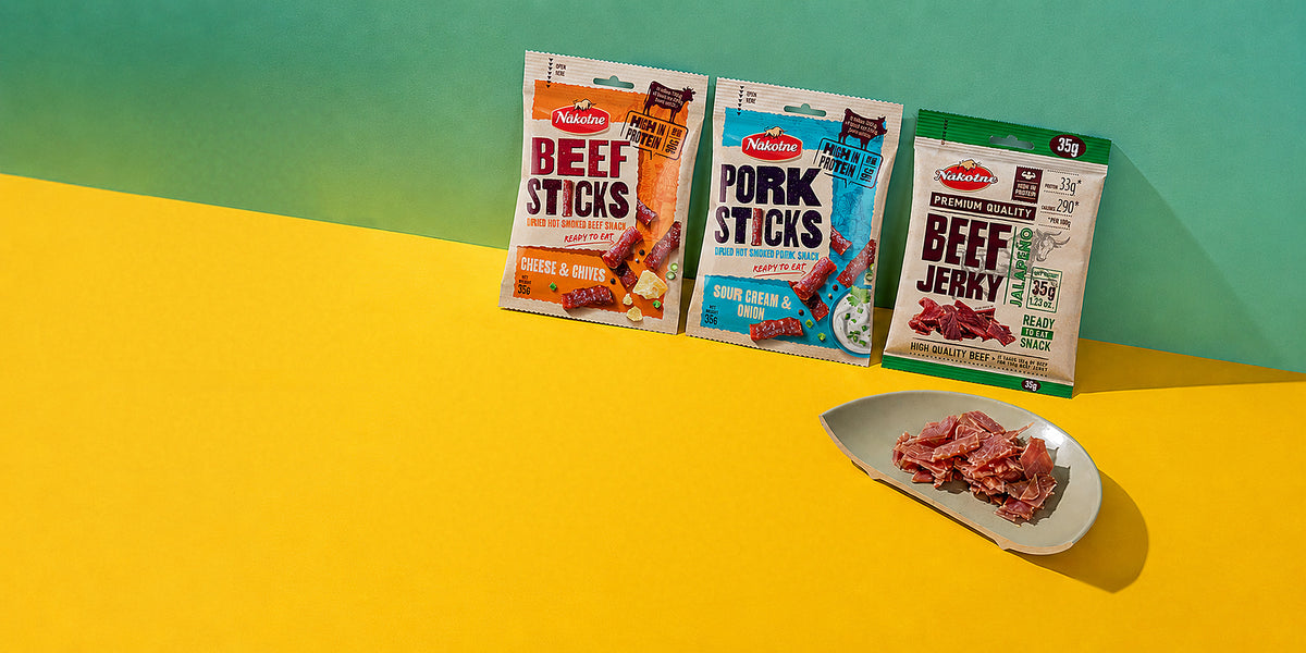 NAKOTNE beef and pork sticks and beef jerky on a yellow table